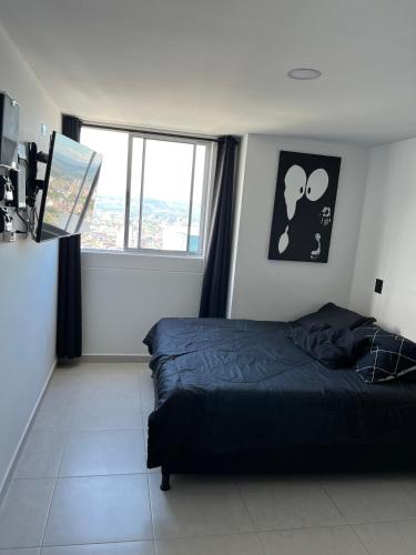 een slaapkamer met een bed en een groot raam bij Apartamento privado con vista en el centro de B/ga in Bucaramanga