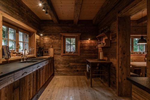 a kitchen in a log cabin with wooden walls at Luxury old wood mountain chalet in a sunny secluded location with gym, sauna & whirlpool in Scheffau am Wilden Kaiser