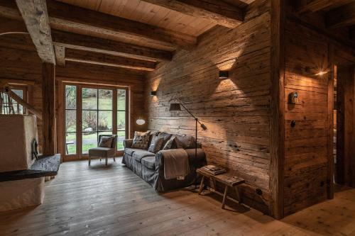 a living room with a couch and wooden walls at Luxury old wood mountain chalet in a sunny secluded location with gym, sauna & whirlpool in Scheffau am Wilden Kaiser