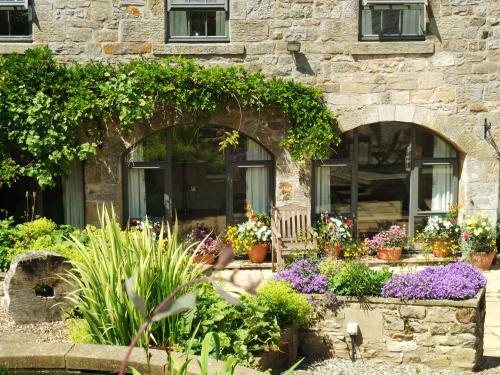 a stone house with flowers and plants in front of it at The Steadings in Morpeth