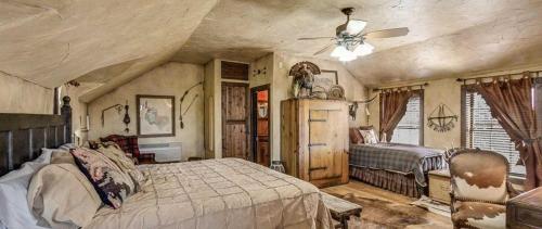 Schlafzimmer mit einem Bett und einem Deckenventilator in der Unterkunft Last Outpost Bandera Ranch House in Bandera