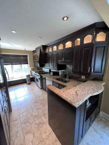 a kitchen with dark wood cabinets and a counter top at Lady Eden Waterfront Mansion - No party in Montréal