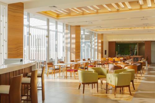三寶壟的住宿－三寶壟新邦利馬快捷假日酒店，餐厅设有桌椅和窗户。