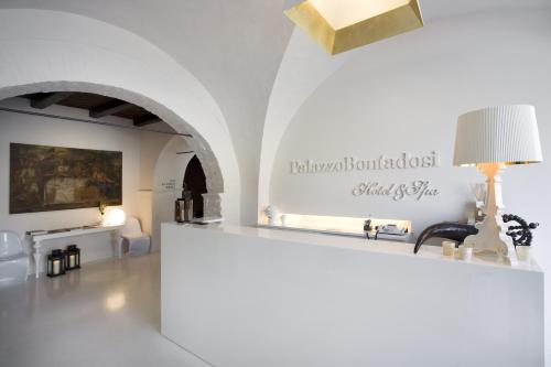 ein weißes Zimmer mit einem Tisch und einer Lampe in der Unterkunft Palazzo Bontadosi Hotel & Spa in Montefalco