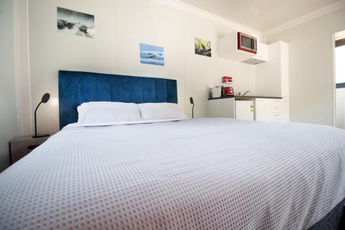 a bedroom with a large white bed with a blue headboard at The Hideaway - On-site Hot Tub - Close to town in Queenstown