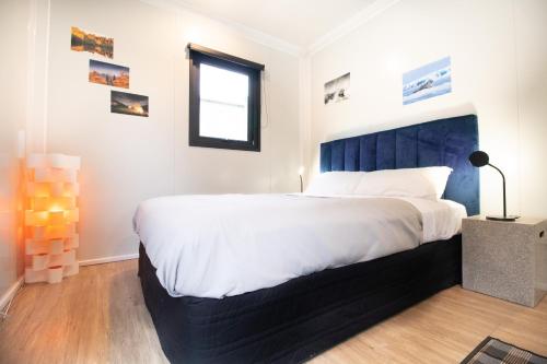 a bedroom with a large bed with a blue headboard at The Hideaway - On-site Hot Tub - Close to town in Queenstown