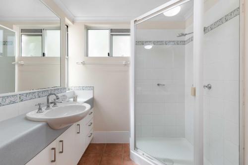 a white bathroom with a sink and a shower at Rivershores in Noosaville