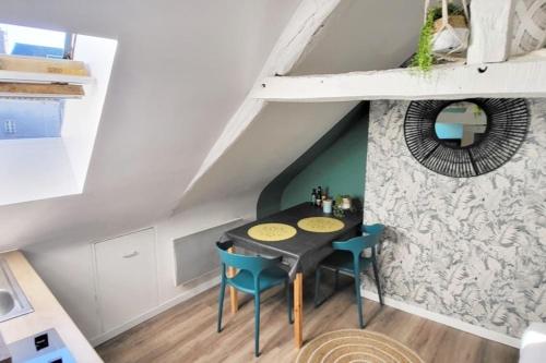 une petite salle à manger avec une table noire et des chaises bleues dans l'établissement La Cabane - Petit studio mansardé - Plage 50m - Rue gratuite, à Saint-Malo
