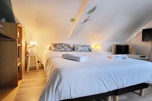 une chambre avec un grand lit blanc dans un grenier dans l'établissement La Cabane - Petit studio mansardé - Plage 50m - Rue gratuite, à Saint-Malo