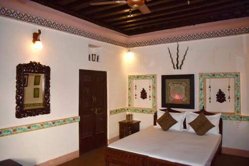 een slaapkamer met een bed en een spiegel aan de muur bij Haveli in Jodhpur