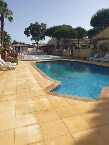 a swimming pool in a resort with a tile floor at Gites Le Pressoir in Vias