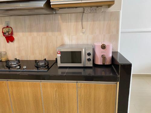 una cocina con microondas y un aparato rosa en una encimera en Teratak Nenda, en Ampang