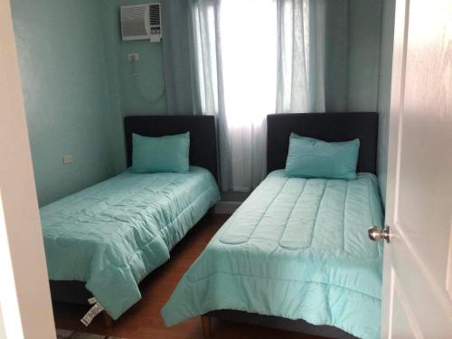 a bedroom with two beds with blue sheets and a window at Caza De Sierra-Home Staycation in Cebu City
