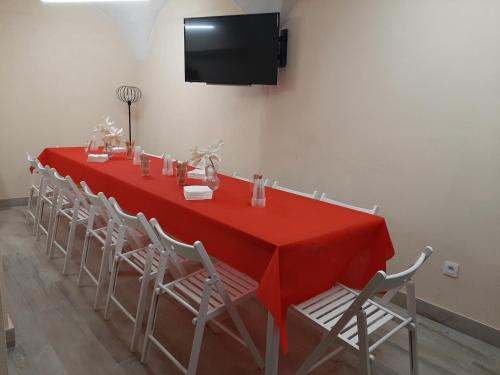 una larga mesa roja con sillas y TV en La Morada de Moret, en Cáceres