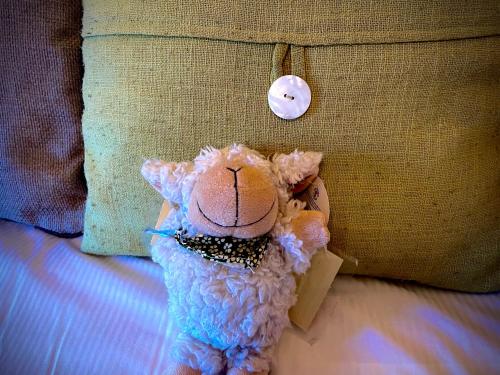 a stuffed animal sitting on a bed next to a pillow at Glenville House - Adults Only - Incl FREE off-site health club with swimming pool, hot tub, sauna & steam room in Windermere