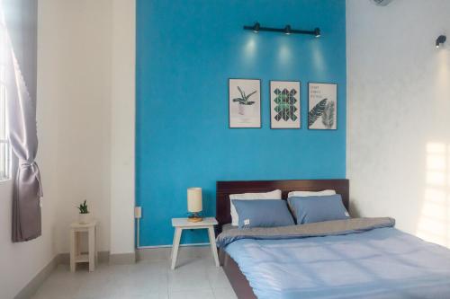 um quarto com uma parede azul e uma cama em Gikgo Can Tho em Can Tho