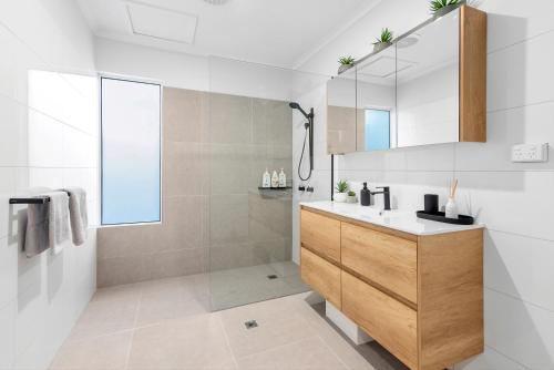 a bathroom with a sink and a mirror at Sandpipers Beach House in Palm Cove