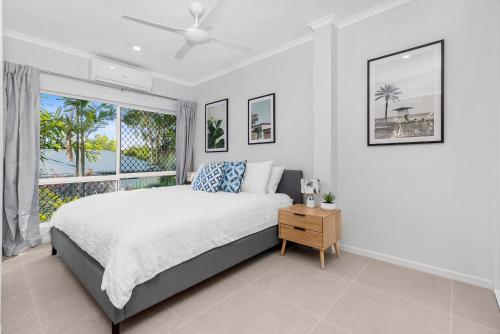a bedroom with a bed and a large window at Sandpipers Beach House in Palm Cove