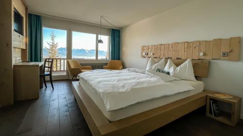 a bedroom with a large white bed and a kitchen at Kräuterhotel Edelweiss in Rigi Kaltbad