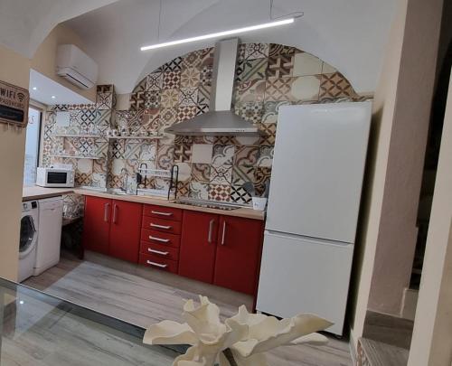 cocina con armarios rojos y nevera blanca en La Morada de Moret, en Cáceres