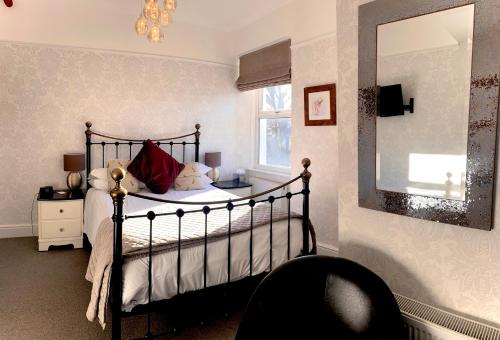 a bedroom with a bed and a mirror and a chair at Glenville House - Adults Only - Incl FREE off-site health club with swimming pool, hot tub, sauna & steam room in Windermere