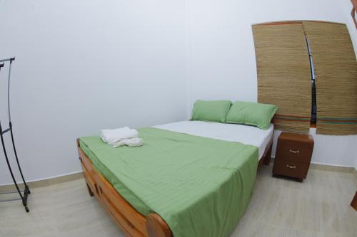 a bedroom with a bed with green sheets and a tripod at Amis Hotel & Restaurant in Jaffna