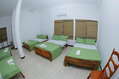a room with two beds and a table and chairs at Amis Hotel & Restaurant in Jaffna