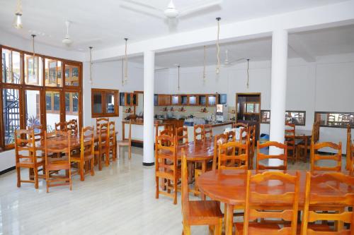 jadalnia z drewnianymi stołami i krzesłami w obiekcie Amis Hotel & Restaurant w mieście Dżafna