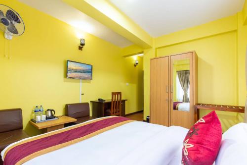 a bedroom with a large white bed and yellow walls at Deepjyoti Inn in Pashupatināth