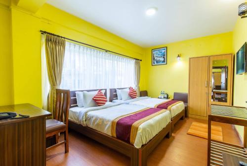 a bedroom with a large bed with yellow walls at Deepjyoti Inn in Pashupatināth