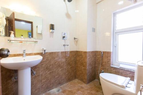 a bathroom with a sink and a toilet and a window at Deepjyoti Inn in Pashupatināth
