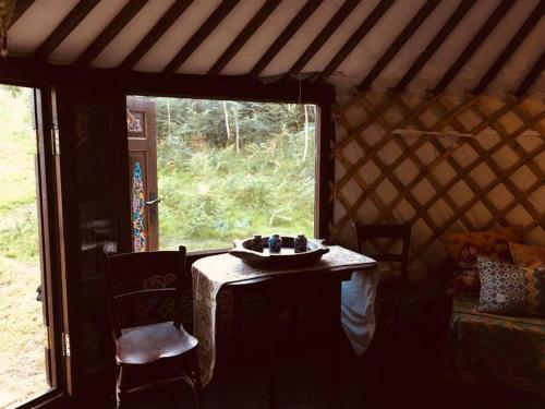 a room with a table in a yurt with a window at Mongolian yurt sleeping 2+2 with outdoor space in Llanbrynmair