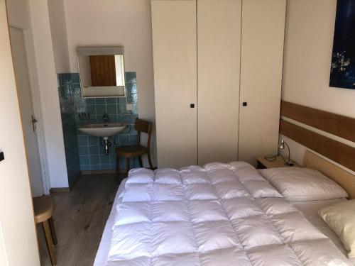 1 dormitorio con 1 cama blanca grande y lavamanos en Breiten 1, en Mörel