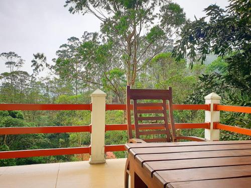 een houten tafel en een stoel op een veranda bij Delhousie Hotel in Nallathanniya