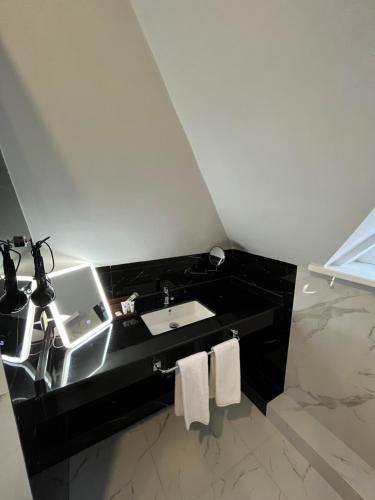 a bathroom with a sink and a black counter at Resident Hotel Kaskelen in Qaskeleng