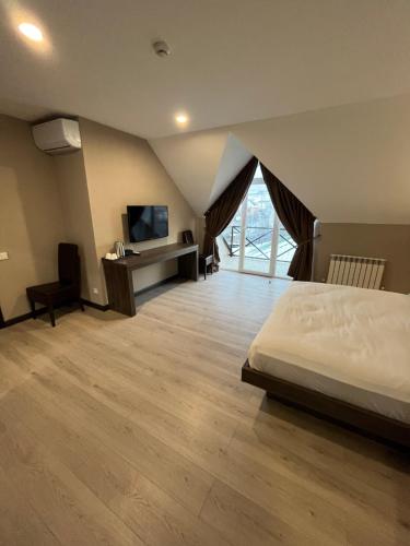 a bedroom with a bed and a desk and a television at Resident Hotel Kaskelen in Qaskeleng