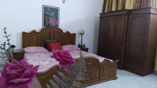 a bedroom with a bed and a cabinet and purple flowers at Leisure home in Colombo