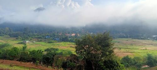 a foggy hillside with a village in the middle of a field at Samoeng fishing park home stay in Samoeng