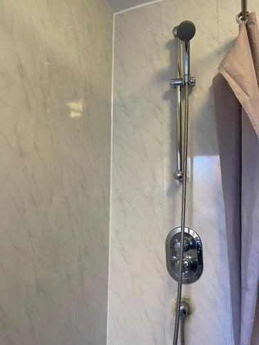 a shower with a shower head in a bathroom at Beautiful Private Rooms in London Central Willesden Green in London