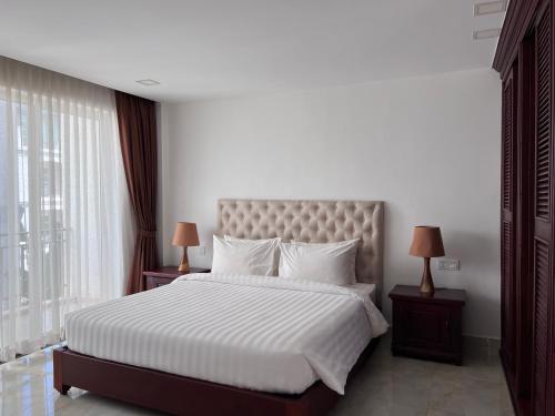 1 dormitorio con 1 cama grande con sábanas y almohadas blancas en SSK Apartment en Siem Riep