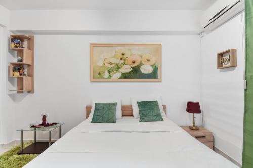 ein Schlafzimmer mit einem weißen Bett und einem Gemälde an der Wand in der Unterkunft Central Studio Emerald in Bukarest