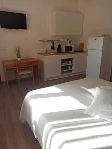 a bedroom with a white bed and a kitchen at Piazza San Giorgio in Dolianova