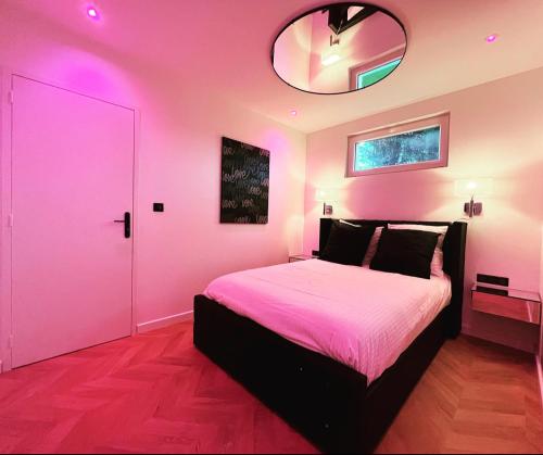 Habitación de color rosa con cama y espejo en Léa Room - Gîte Romantique - Jacuzzi, en Bourguébus