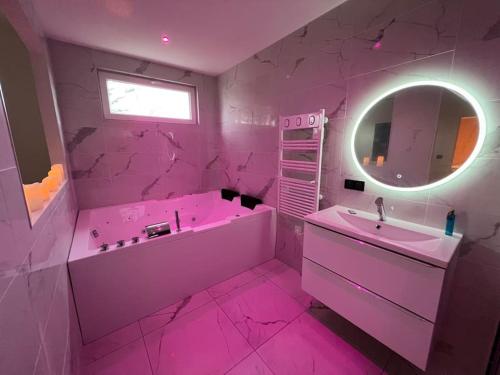 Léa Room - Gîte Romantique - Jacuzzi في Bourguébus: حمام وردي مع حوض ومغسلة