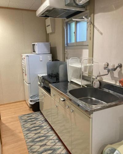 a kitchen with a sink and a refrigerator at エスポアールあま in Ama