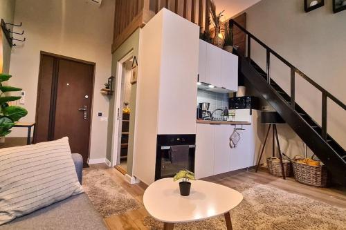 a living room with a couch and a table and a staircase at Downtown studio-loft in Constanţa