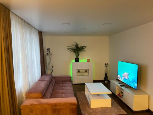 a living room with a brown couch and a flat screen tv at Very welcome apartment in Panevėžys