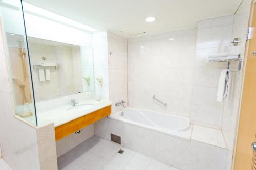 a white bathroom with a tub and a sink at Ardi Hotel in Yuanlin