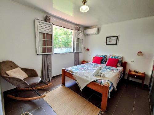 um quarto com uma cama, uma cadeira e uma janela em Villa Bwa Kanpech' em Le Vauclin