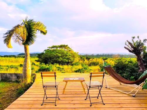 a wooden deck with chairs and a table and a hammock at ハレマヤ 一軒家 Haremaya in Ishigaki Island